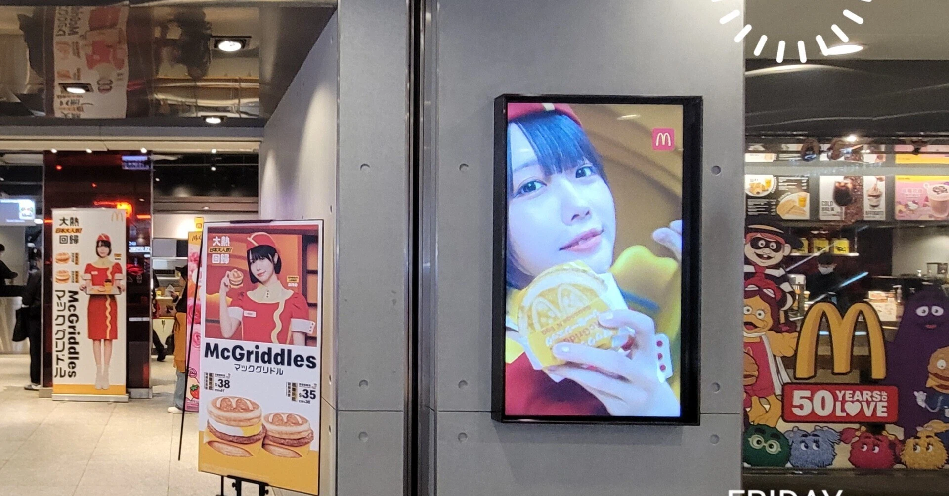 あのちゃんが香港マクドナルドの制服を着て微笑む広告ボード。店舗前に設置されている。