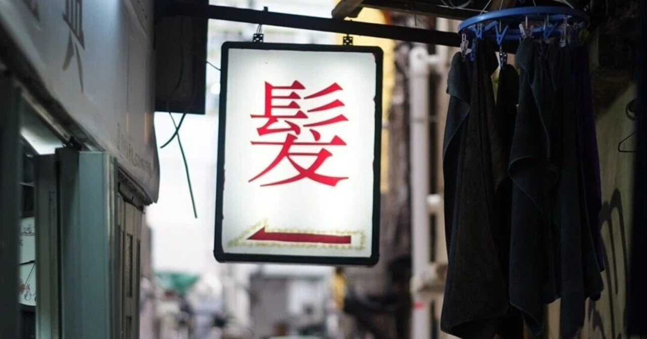「髪」という漢字一文字が大きく書かれた、香港の上海理髪店のレトロな看板。長年の歴史を感じさせる佇まい。