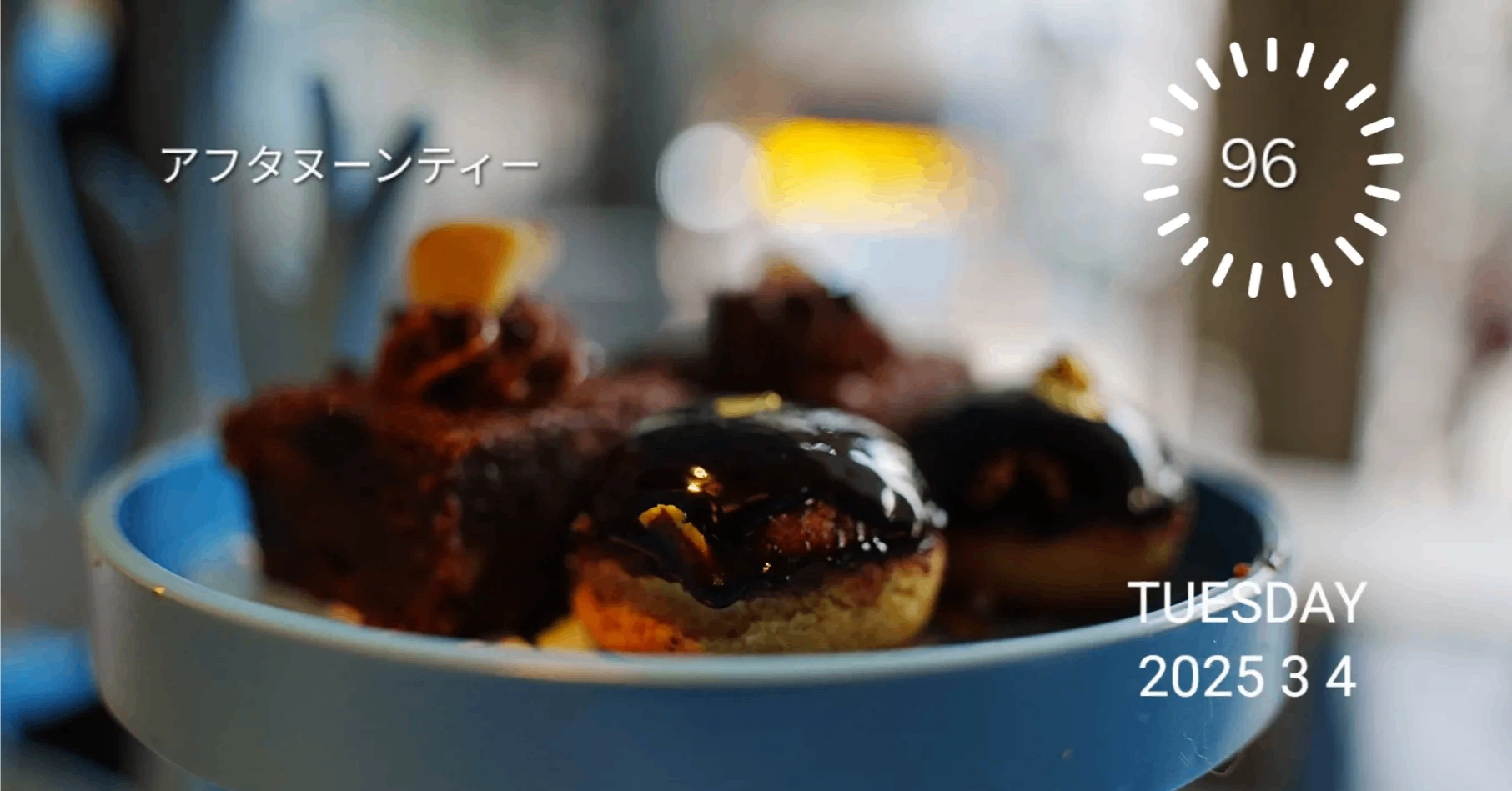 白いテーブルに置かれた、三段重ねの銀製ティースタンド。サンドイッチ、スコーン、色とりどりのケーキが美しく盛り付けられている。