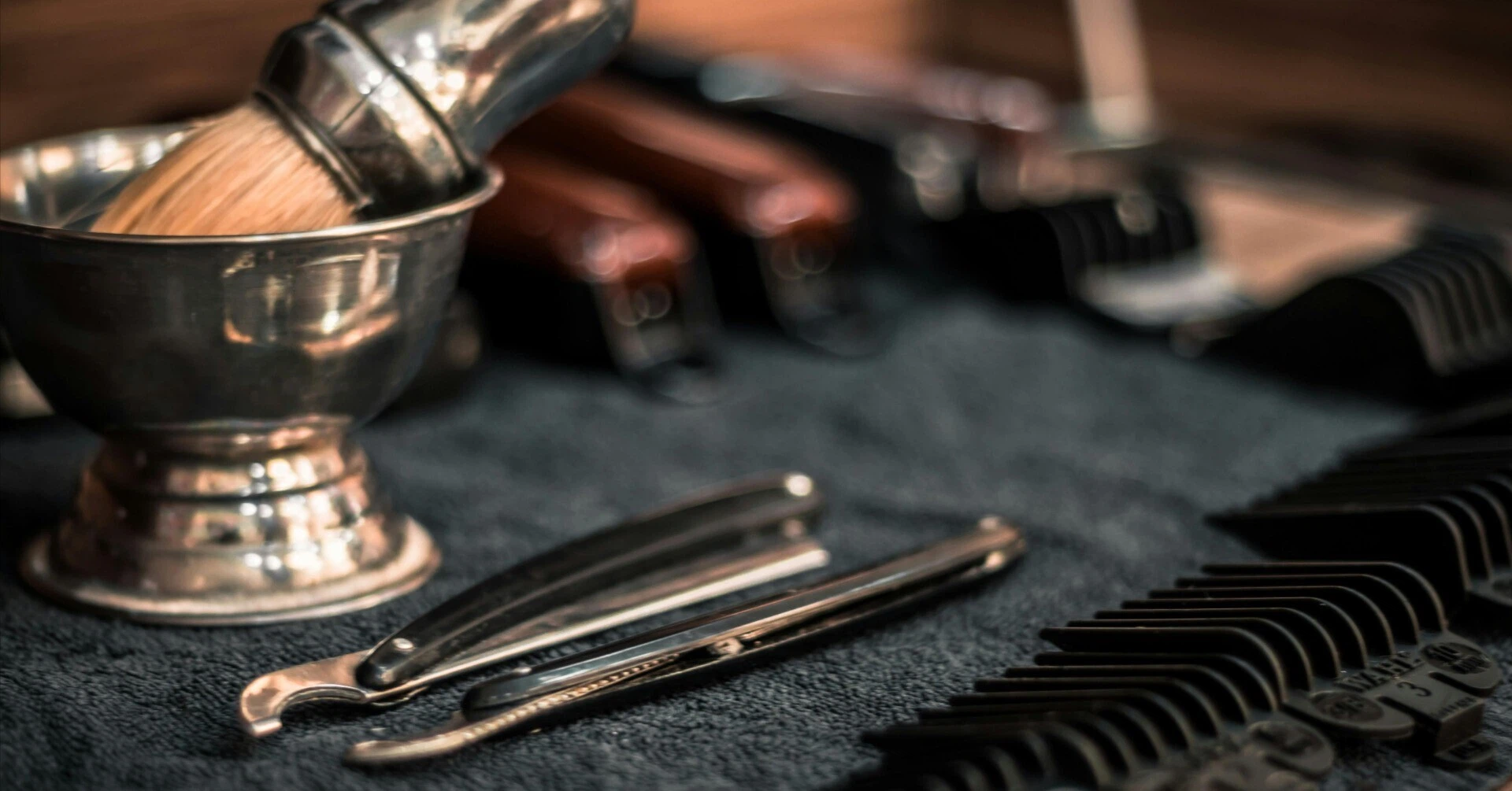 Close-up of vintage shaving brush, straight razor, and clipper guards in a barber shop