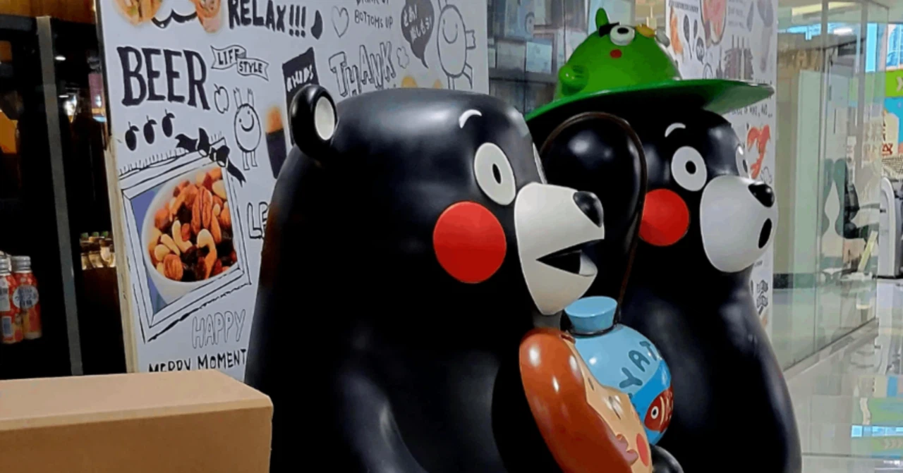 香港のスーパーマーケットの通路脇に置かれている、くまモンともう一体のキャラクターの像。手前には段ボール箱がある。