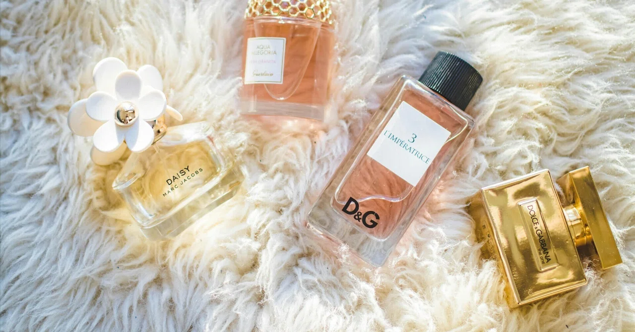 European luxury brand perfume bottles, such as Dolce & Gabbana and Guerlain, arranged on a white faux fur rug