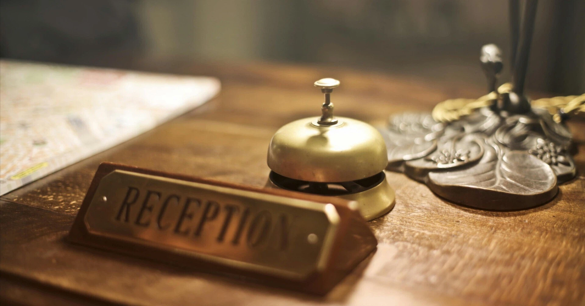 A classic hotel reception bell and a "RECEPTION" sign placed on a wooden front desk