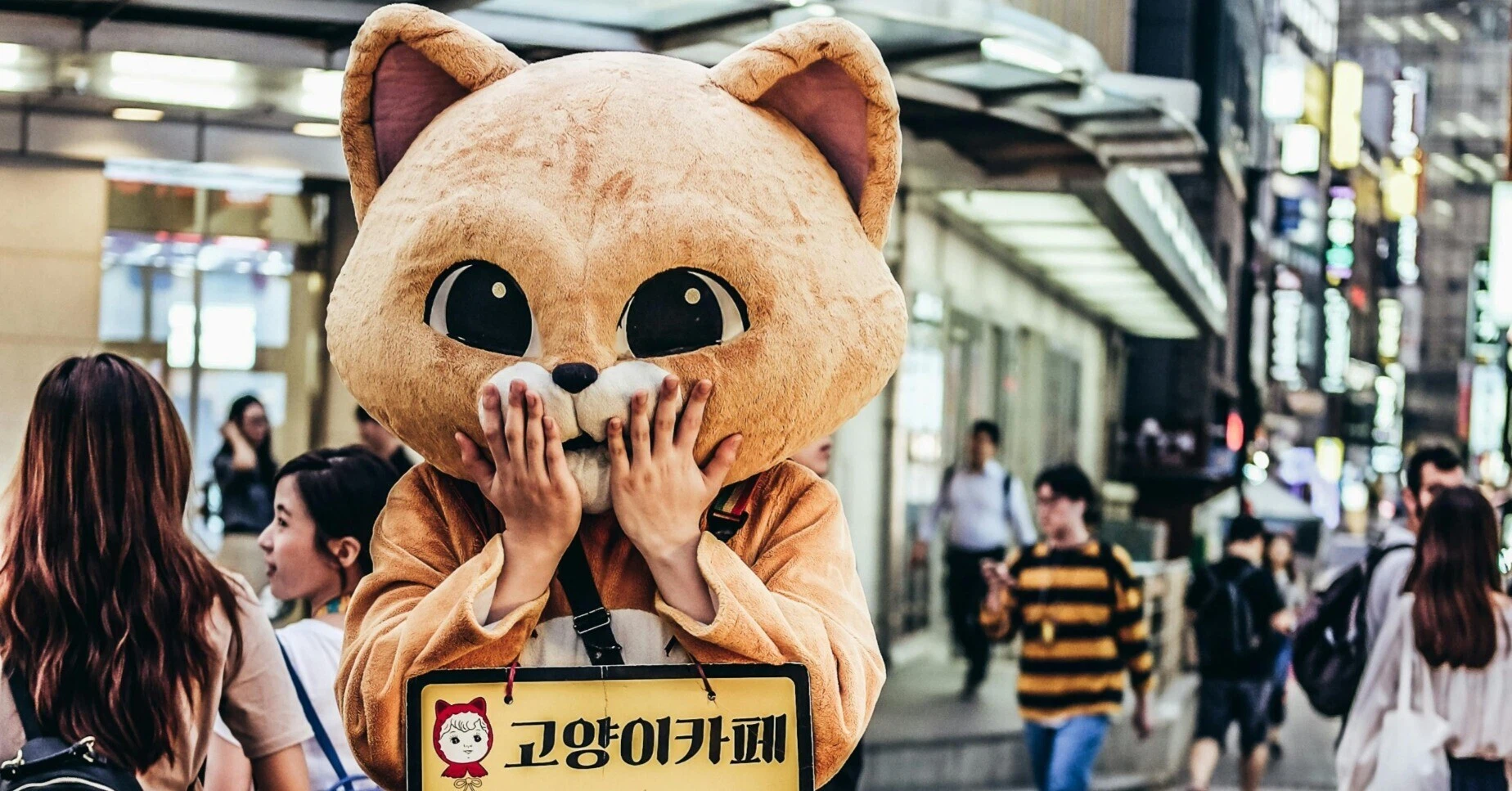 街中で人々の視線を集める、驚いたポーズの猫の着ぐるみ