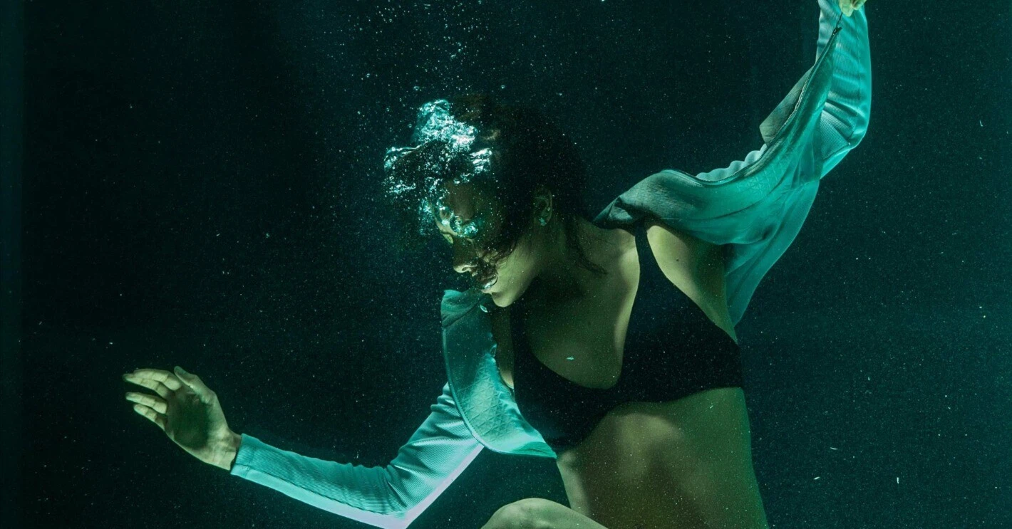 A woman diving deep underwater, representing a fully engaging immersive experience