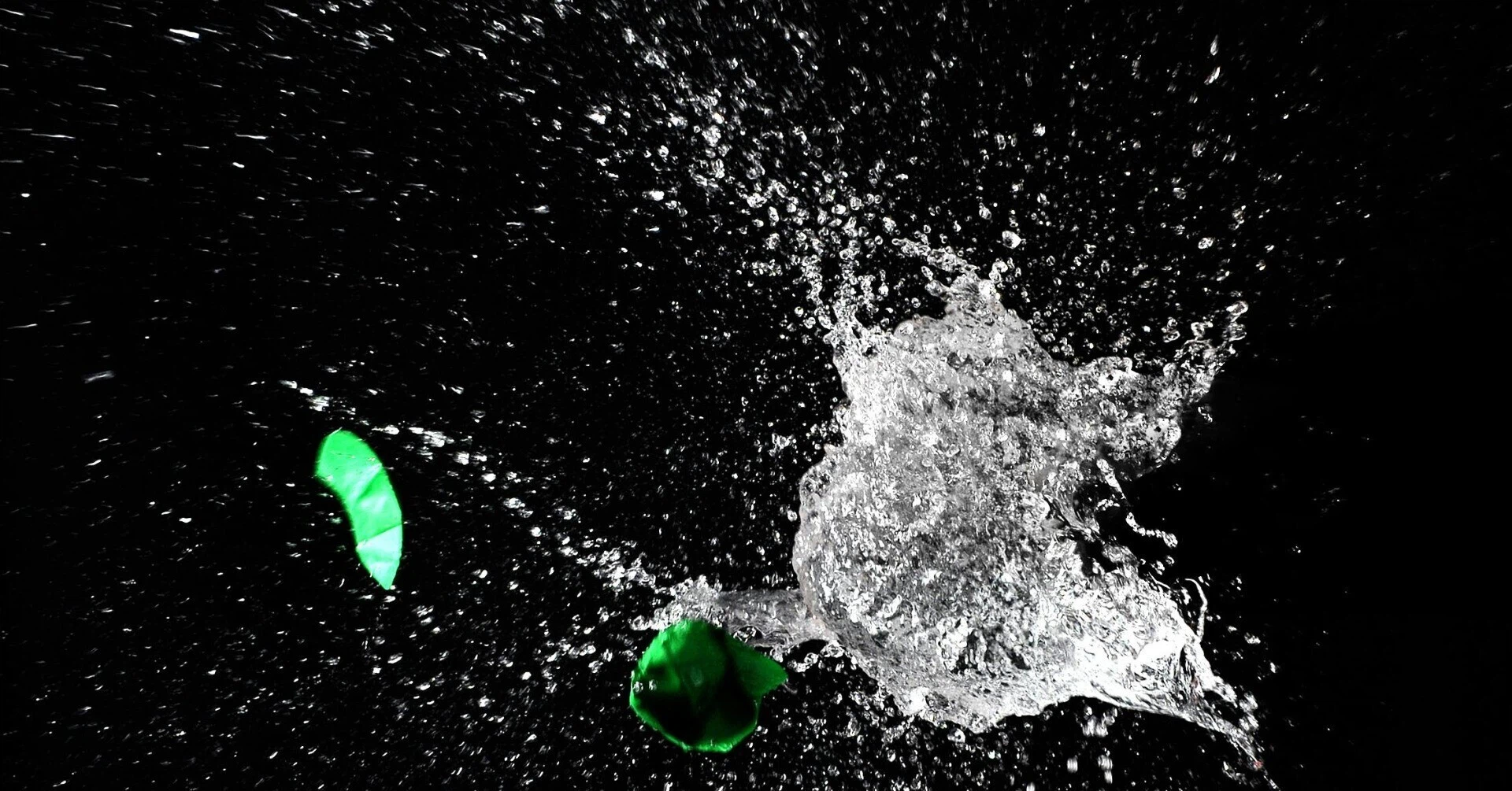 暗闇で水風船が割れ、水しぶきが激しく弾ける瞬間のハイスピード写真