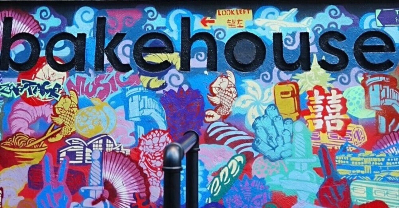 カラフルなグラフィティアートが描かれたレンガ壁にデザインされたbakehouse(ベイクハウス)のロゴ