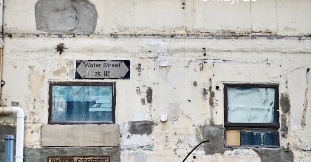 古びた建物の外壁に設置された「水街 (Water Street)」の道路標識と古い窓枠